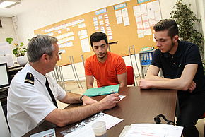 un administratif du Centre d'Information et de Recrutement des Forces Armées renseigne deux jeunes hommes sur les opportunités de recrutement
