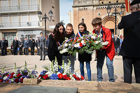Enfants déposant une gerbe de fleur devant la stèle square du Souvenir Français.