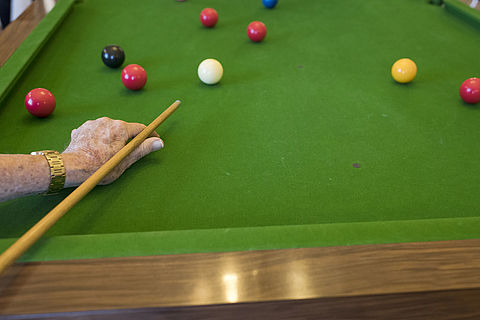 Une personne âgée joue au billard