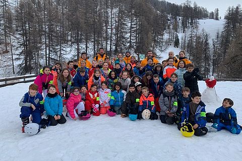 les jeunes skieurs en compagnie de leurs encadrants pausent en groupe sur la neige